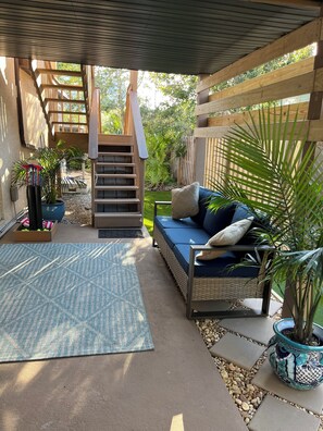 A covered outdoor seating area with a sofa, a staircase, and potted plants. - 3-bedroom house short walk to beach with rooftop deck, putting green (St. Augustine)