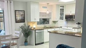 Una cocina moderna con una isla central, muebles blancos y un ventilador de techo.