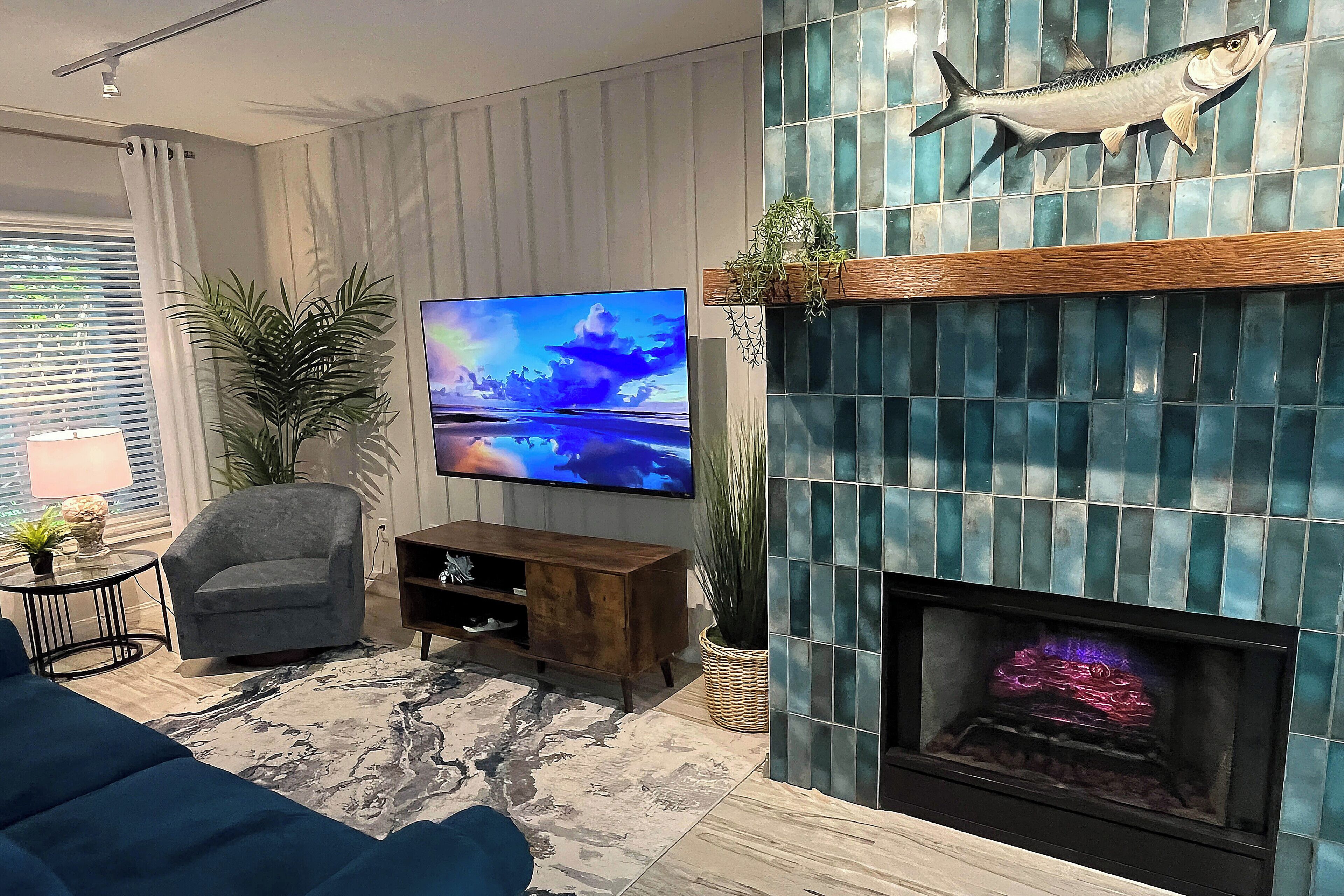 A living room with a TV, a fireplace, a sofa, and a plant.