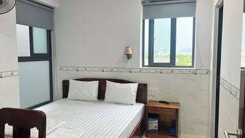 Ein Schlafzimmer mit Bett, Nachttisch, Fenster und einer Wandlampe.
