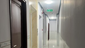A corridor with a door, a sign indicating an exit, and a ceiling-mounted light fixture.