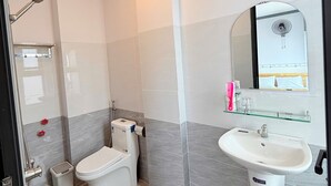 A modern bathroom with a shower, toilet, and sink, featuring a glass shelf with toiletries.