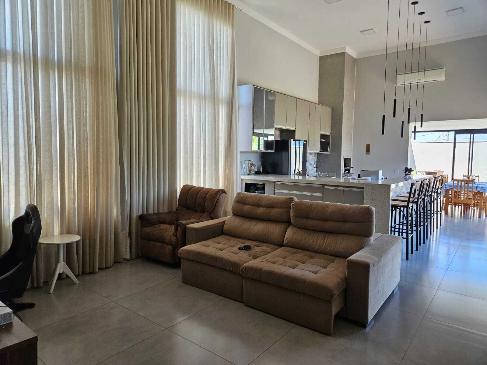 A modern living room with a sofa, a dining area, and a kitchen in the background.