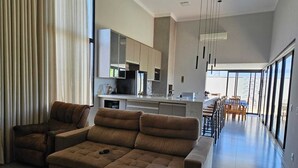 Una sala de estar moderna con un sofá, un comedor con sillas y una cocina con armarios.