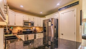 A modern kitchen with white cabinets, stainless steel appliances, and a granite countertop.