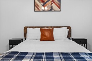 A bed with a wooden headboard, white and brown pillows, a plaid blanket, and two nightstands. - Bella Vista Getaway - Near Oz Downhill Bike Park! (Bella Vista)