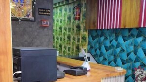 A reception desk with a wooden finish, a ceiling fan, and a wall with geometric patterns.
