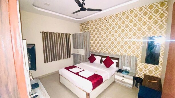 A bedroom with a bed, a ceiling fan, a patterned wall, and a nightstand.
