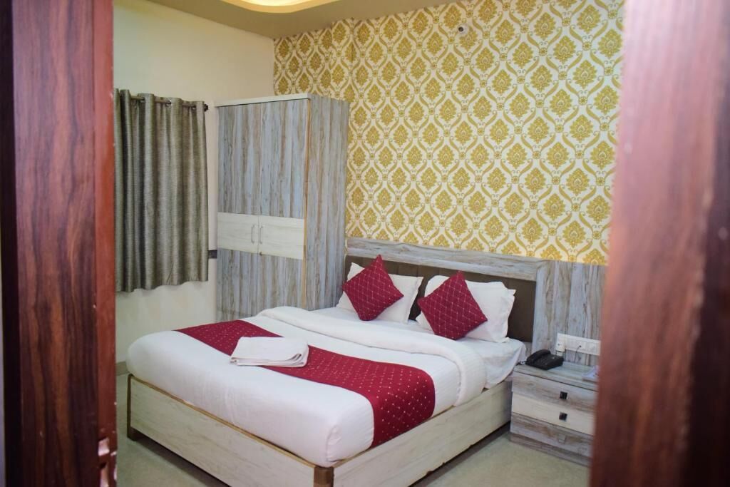 A bedroom with a bed, a nightstand, a wardrobe, and a patterned wall.