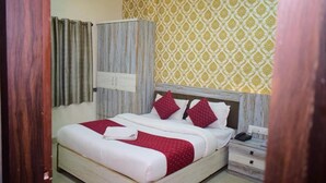 A bedroom with a bed, a nightstand, a wardrobe, and a patterned wall.