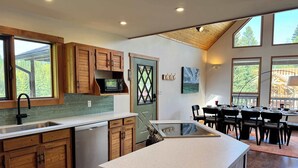 Une cuisine moderne avec des meubles en bois, un lave-vaisselle et un coin repas comprenant une table et des chaises.