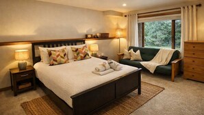 Une chambre à coucher avec un lit, des lampes de chevet, un canapé vert, une commode en bois et une fenêtre avec des rideaux.