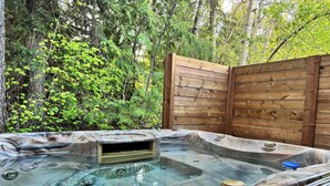 Un bain à remous situé dans un espace boisé, entouré d’une clôture en bois.