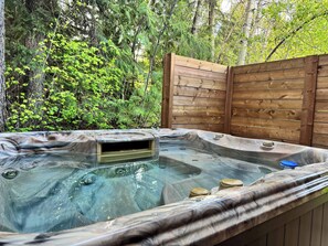 Un bain à remous situé dans un espace boisé, entouré d’une clôture en bois.