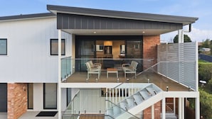 Ein modernes, zweistöckiges Haus mit Balkon, Treppe und Küchenbereich.