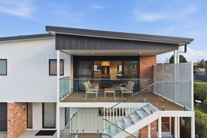 Ein modernes, zweistöckiges Haus mit Balkon, Treppe und Küchenbereich.