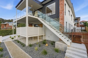 Ein modernes Haus mit einer gläsernen Wendeltreppe, die zu einem überdachten Außenbereich führt.