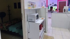 Ein kleines Hotelzimmer mit Kochnische, Bett, Fernseher und Badezimmer.