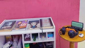 Ein Zimmer mit einer Küchenzeile, einem kleinen Aquarium, einem Tisch mit Büchern und einem Lautsprecher auf einem kleinen Beistelltisch.