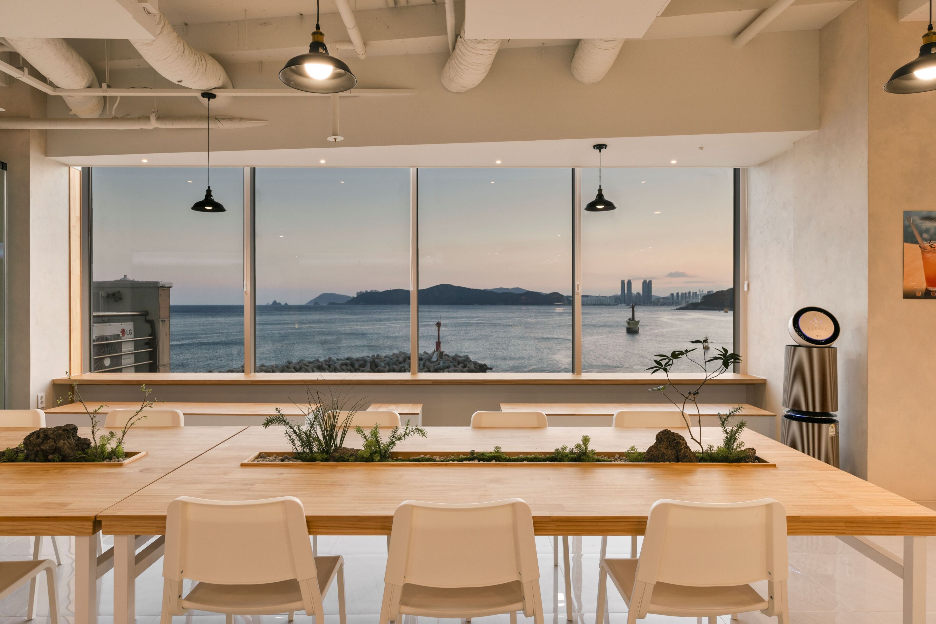 A modern dining area with a large window offering a view of a city skyline and water.