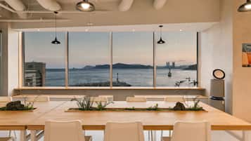 A modern dining area with a large window offering a view of a city skyline and water.