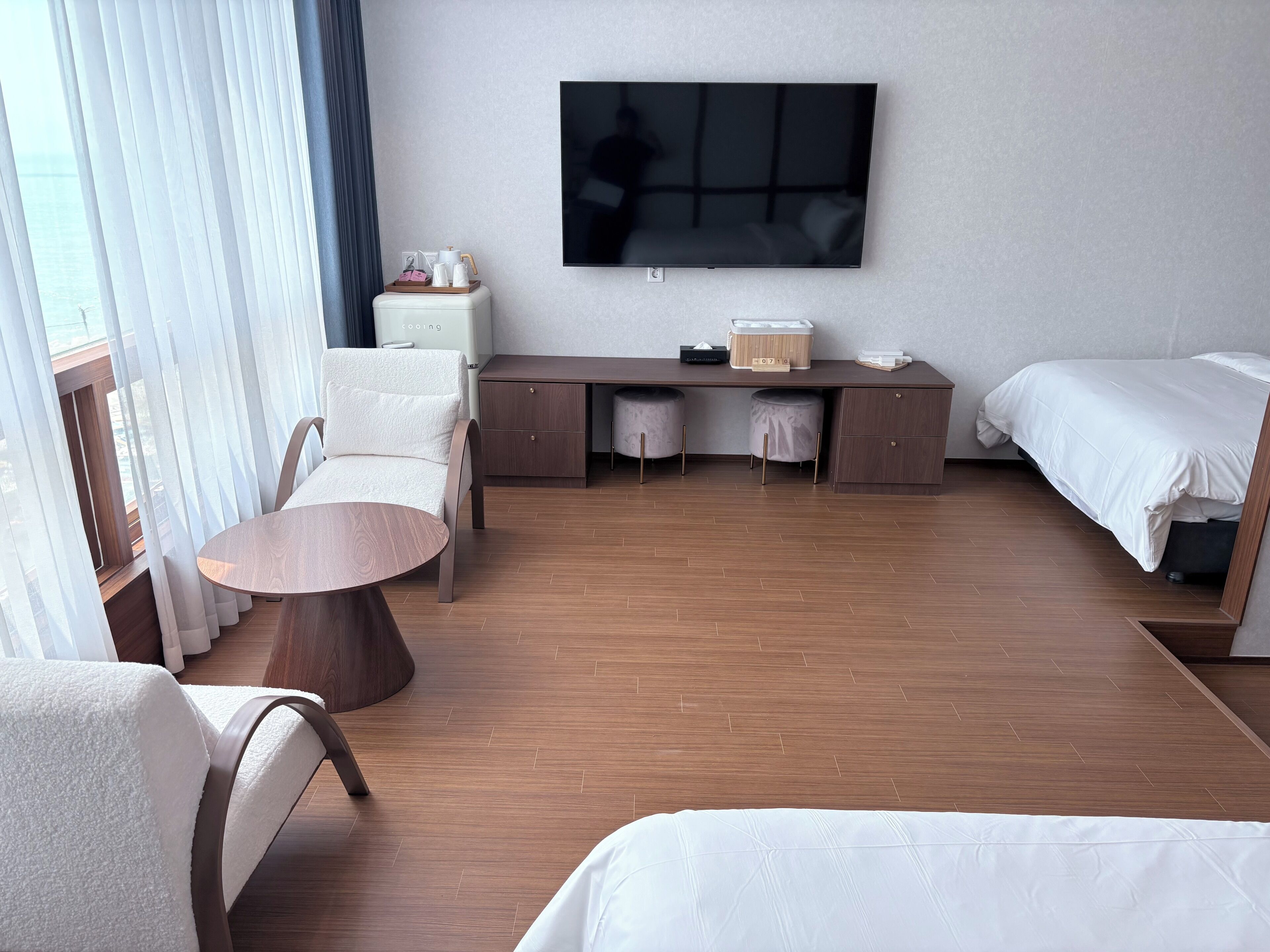 Hotelkamer met een bed, bureau, stoel, televisie en raam met gordijnen.