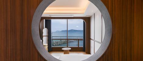 A circular window with a view of a balcony and a body of water.