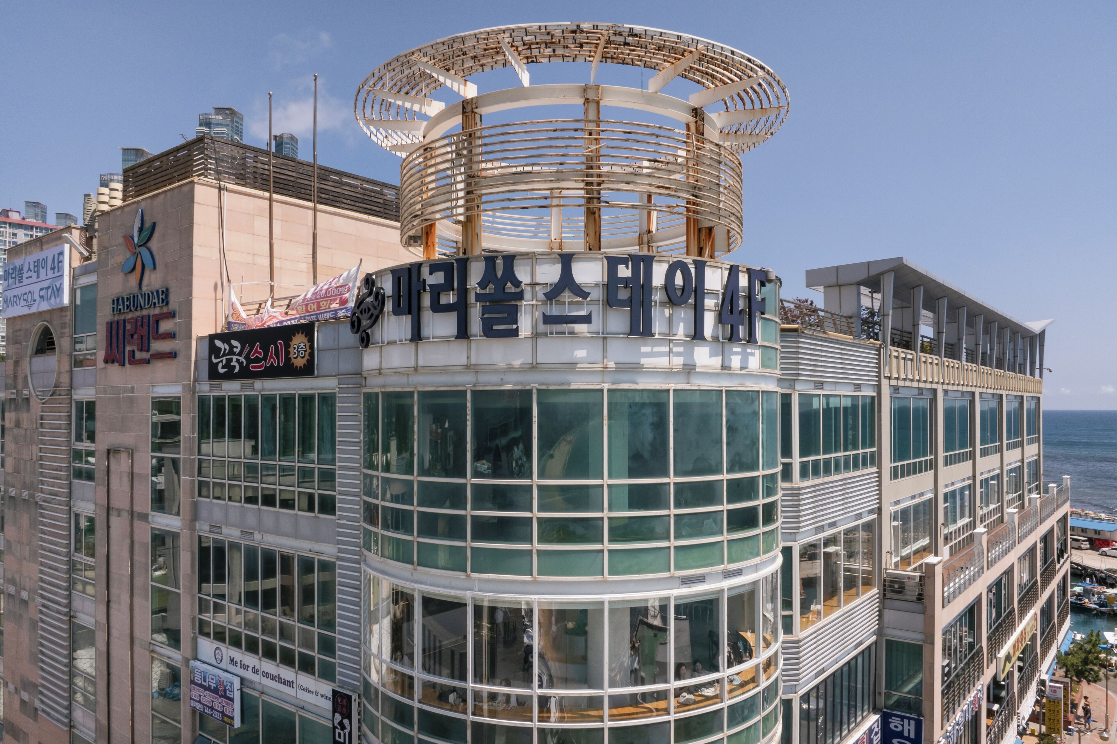 Un edificio moderno con fachada de vidrio circular y un letrero llamativo en la parte superior.