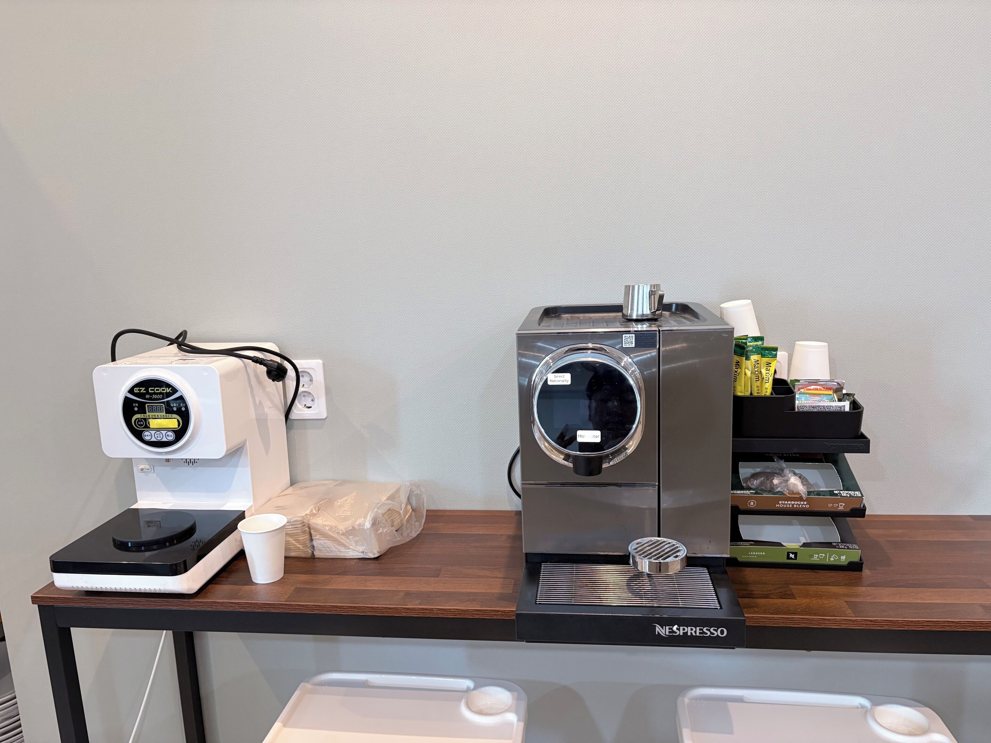 A coffee machine with a digital display and a coffee cup on a wooden table.