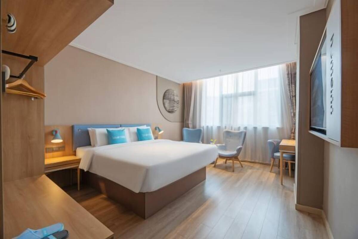 Una habitación de hotel con una cama grande, mesitas de noche, un escritorio y una silla.