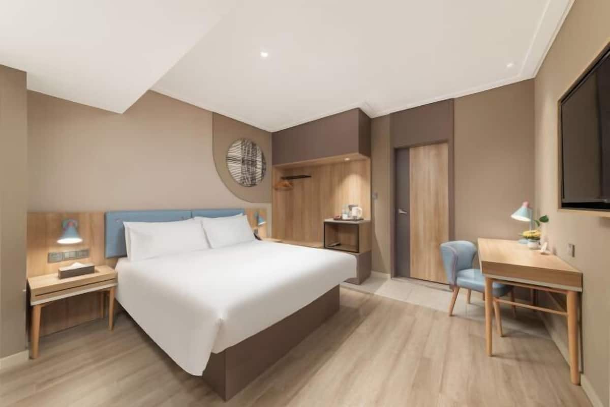 Una habitación de hotel moderna con una cama grande, mesitas de noche, un escritorio y una silla.