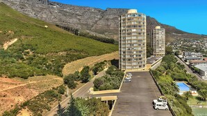 A high-rise hotel with multiple floors, a parking lot, and a mountainous backdrop. - Table Mountain Escape, Mountain and sea Views (Cape Town)