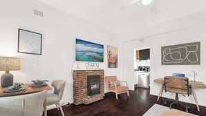 A modern living room with a fireplace, a dining area, and a kitchen. - Boutique Apartment in Elizabeth Bay (Elizabeth Bay)
