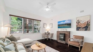 A living room with a fireplace, a sofa, a coffee table, and a dining area. - Boutique Apartment in Elizabeth Bay (Elizabeth Bay)