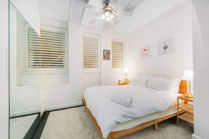 Ein Schlafzimmer mit einem Bett, Nachttischen, einem Deckenventilator und Wandbildern.