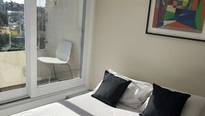 A bedroom with a bed, pillows, a chair, and a window. - 1 bedroom apartment with amazing view (Paddington)