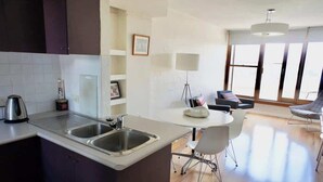 A modern kitchen with a central island, a dining area with a table and chairs, and large windows providing natural light. - 1 bedroom apartment with amazing view (Paddington)