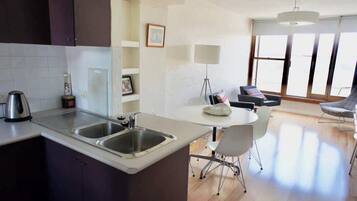 A modern kitchen with a central island, a dining area with a table and chairs, and large windows providing natural light.
