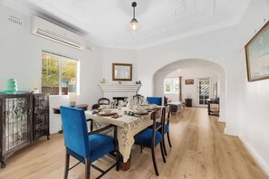 Ein Esszimmer mit Tisch für vier Personen, einem Kamin und einem rundbogigen Durchgang zu einem weiteren Raum.