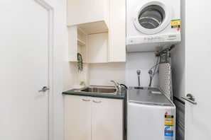 Eine kleine Küche mit Waschmaschine, Spüle und Kühlschrank.