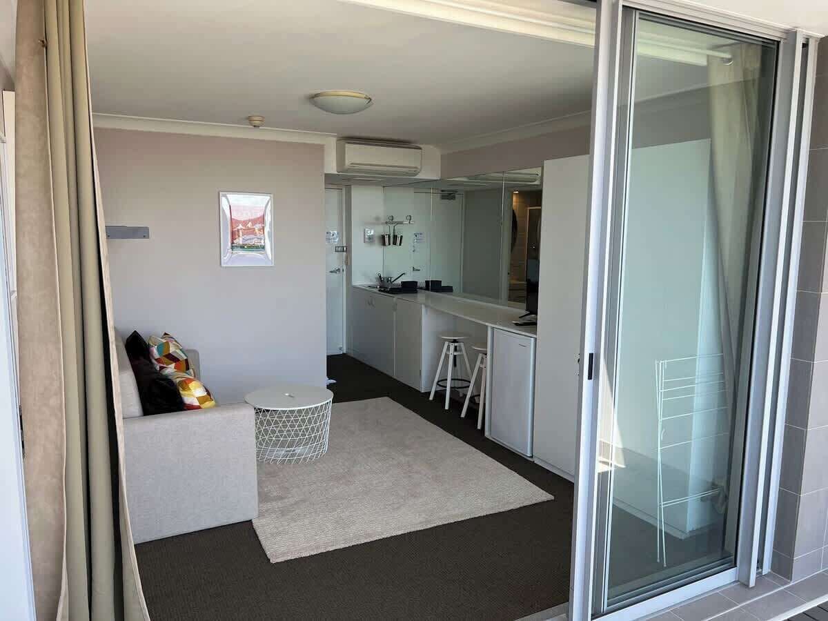 A compact living space with a kitchenette, a seating area, and a sliding glass door leading to an outdoor area.