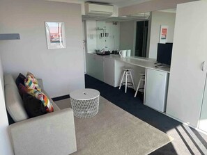 A compact room with a sofa, a small round table, a kitchenette, and a mirror. - Cosy studio with a large balcony and a great view! (Darlinghurst)