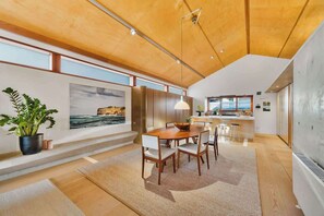 A modern kitchen with a central island, wooden ceiling, and large windows. - Stunning 3-BR Architectural Gem Villa (Watsons Bay)