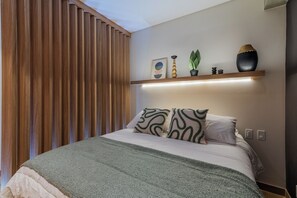 Ein modernes Schlafzimmer mit einem Bett, einem Nachttisch mit Dekoration und einer Wand aus Holzlamellen.