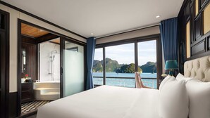 Ein Schlafzimmer mit einem großen Bett, Seeblick, einem Badezimmer mit Badewanne und Holzboden.