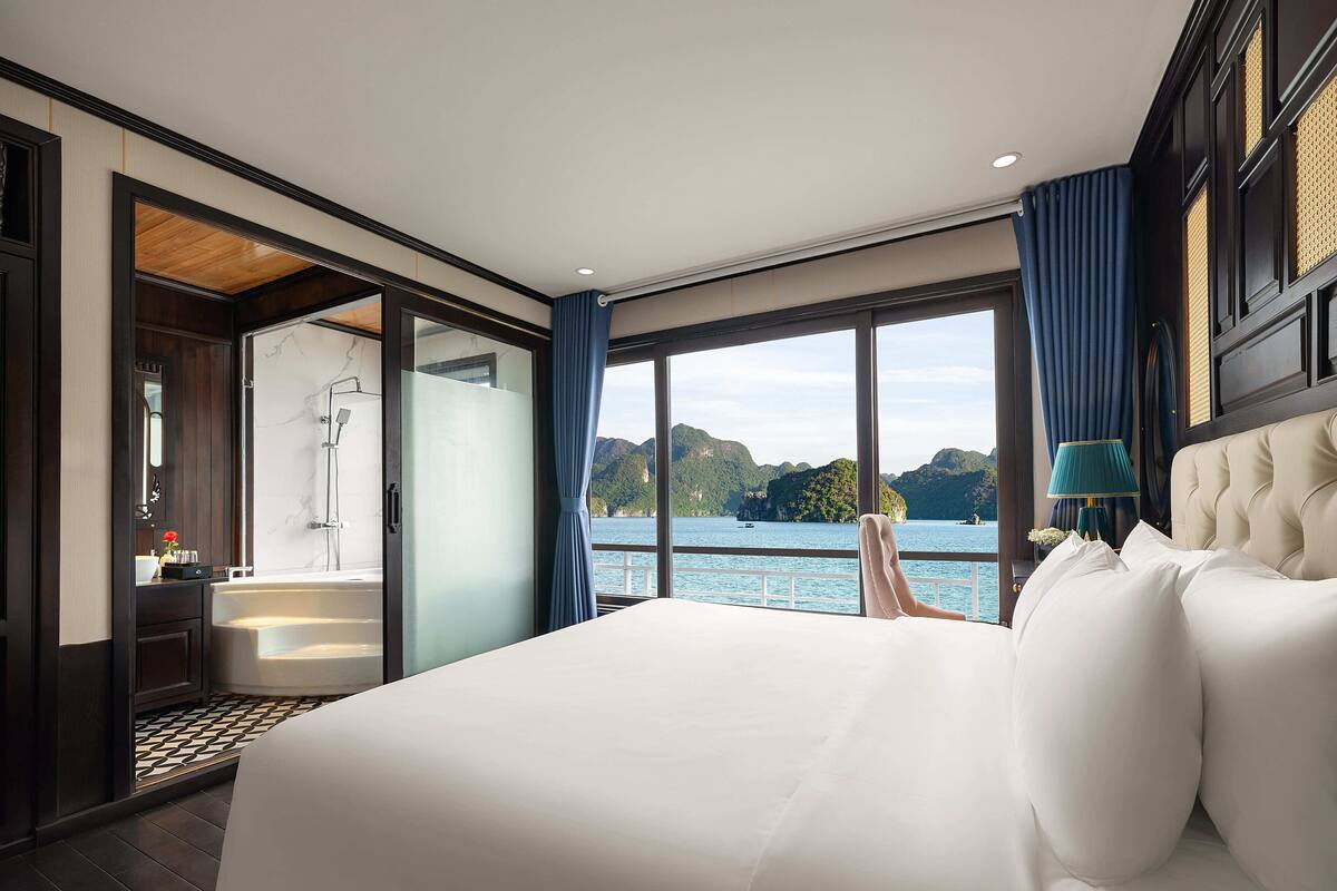 Ein Schlafzimmer mit einem großen Bett, Seeblick, einem Badezimmer mit Badewanne und Holzboden.