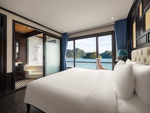 Ein Schlafzimmer mit einem großen Bett, Seeblick, einem Badezimmer mit Badewanne und Holzboden.
