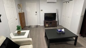 A living room with a sofa, coffee table, TV, and a cabinet. - Spacious Guest Suite in Coquitlam (Coquitlam)