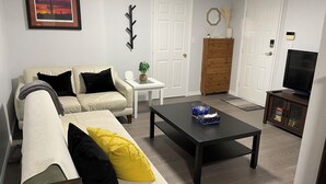 A living room with a sofa, a coffee table, a television, and a cabinet. - Spacious Guest Suite in Coquitlam (Coquitlam)