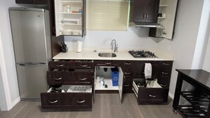 A compact kitchen with a refrigerator, sink, stove, and open cabinets. - Spacious Guest Suite in Coquitlam (Coquitlam)